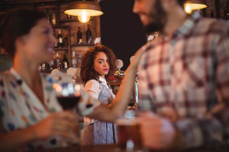 woman looking at couple at bar