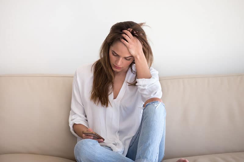 worried young woman looking at phone