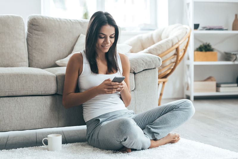 mujer joven enviando mensajes de texto en el suelo