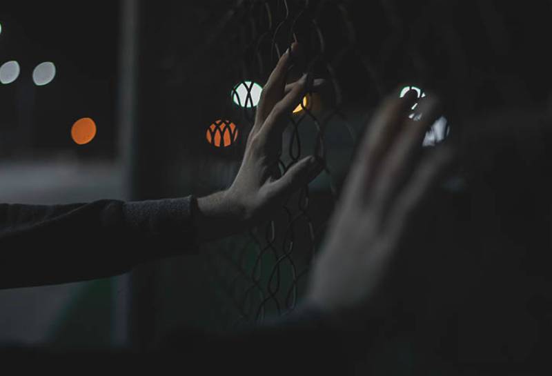 man's hands on fence