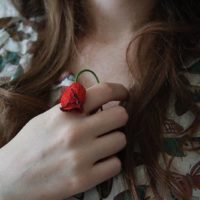 fotografia em grande plano de uma mulher a segurar uma pequena rosa