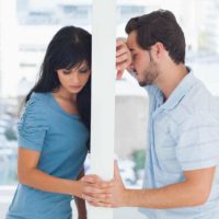 unhappy couple holding hands while leaning on wall