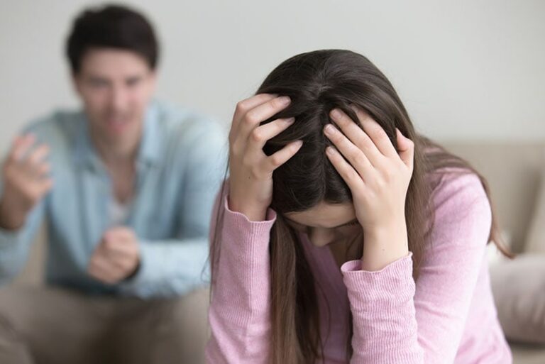 worried woman holding hands on the head while man yelling