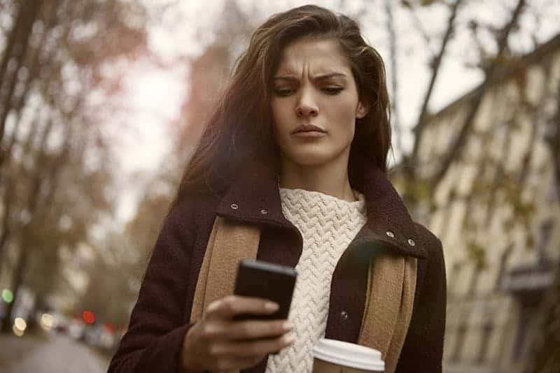 Una chica enfadada mira el teléfono