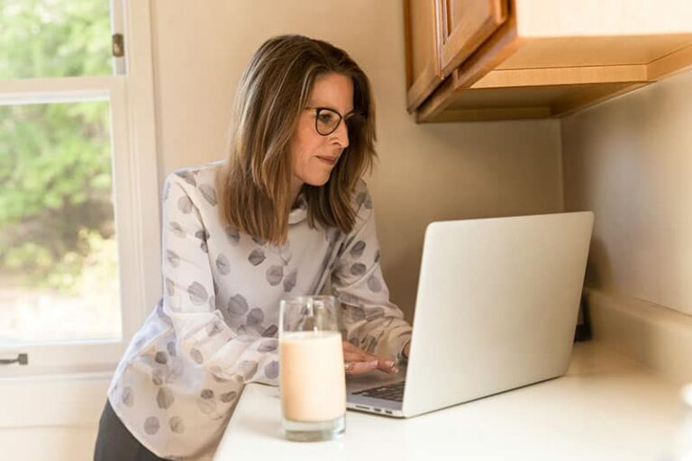 an older woman typing on laptop