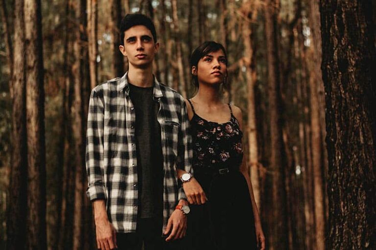 young couple standing outside surrounded by trees