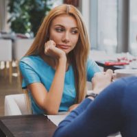 annoyed woman sitting with man at cafe