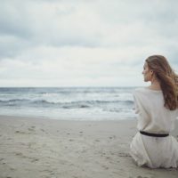 mulher solitária sentada na praia