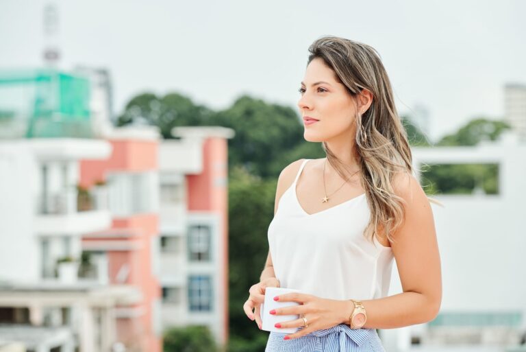 woman standing outdoor alone, holding cup of coffee