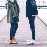 homem e mulher vestindo casaco e de pé em frente um do outro no exterior