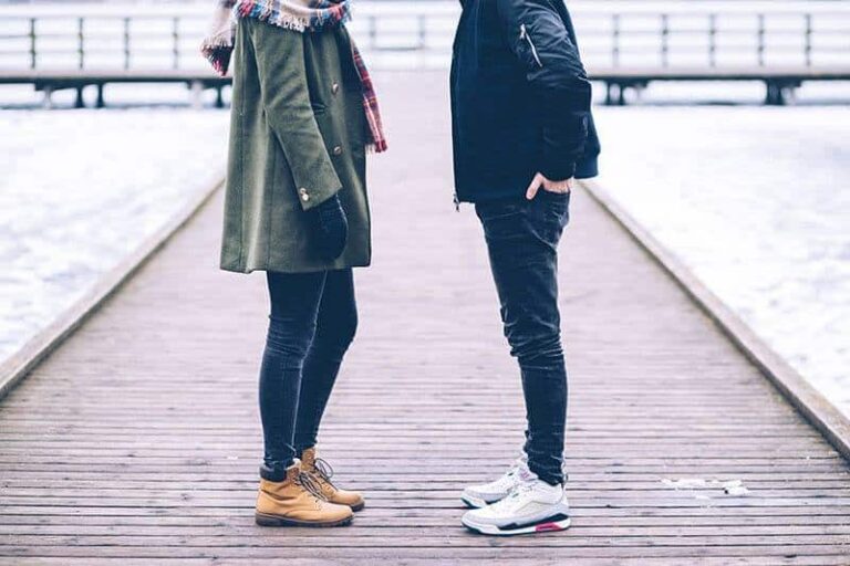 man and woman wearing jacket and standing in front of each other outside