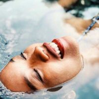 close up photo of smiling woman face lying on water