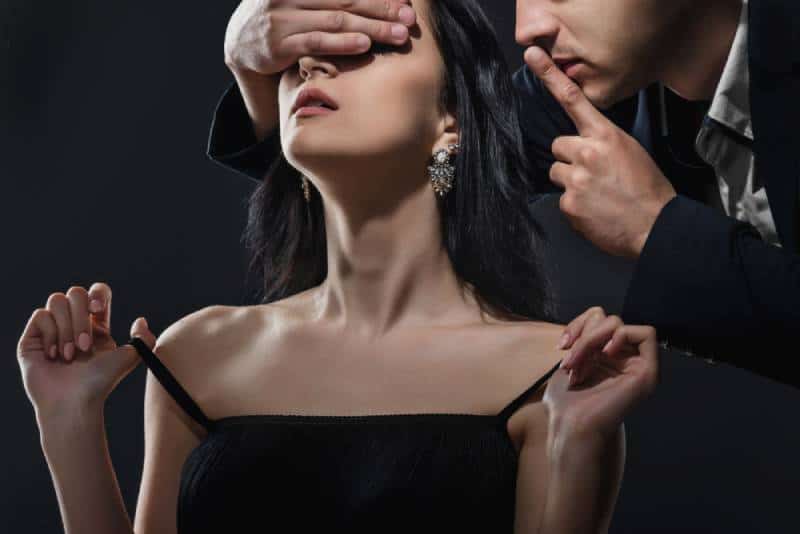 Un uomo mostra un gesto di silenzio a una donna mentre le copre gli occhi