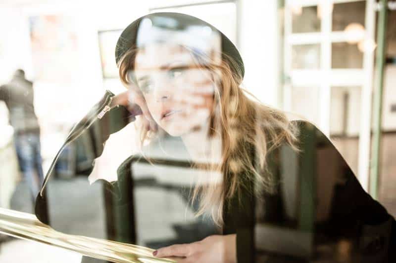 Photo of woman with black hat leaning on brown table