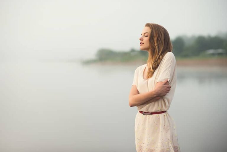 young woman standing by the lake