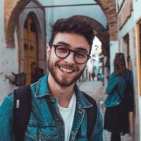 retrato de hombre sonriente con gafas y de pie al aire libre