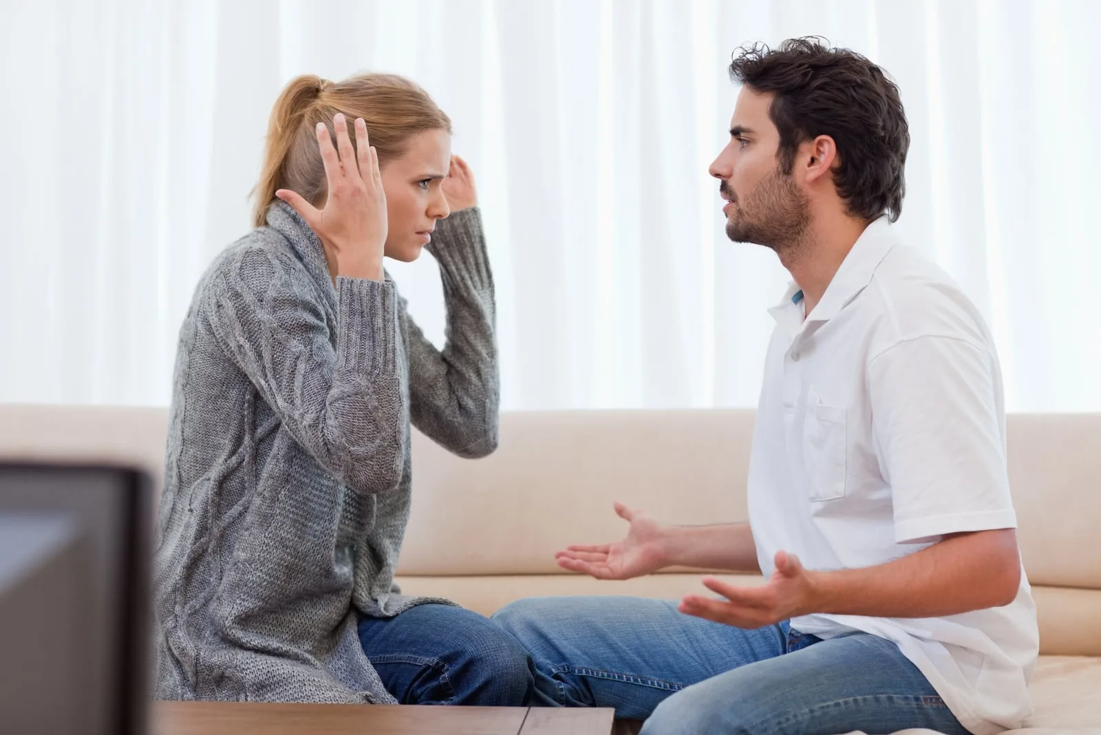 angry blond woman arguing with man on the couch