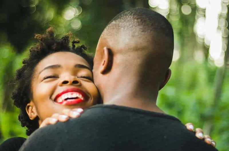 back view of man hugging smiling woman with red lipstick