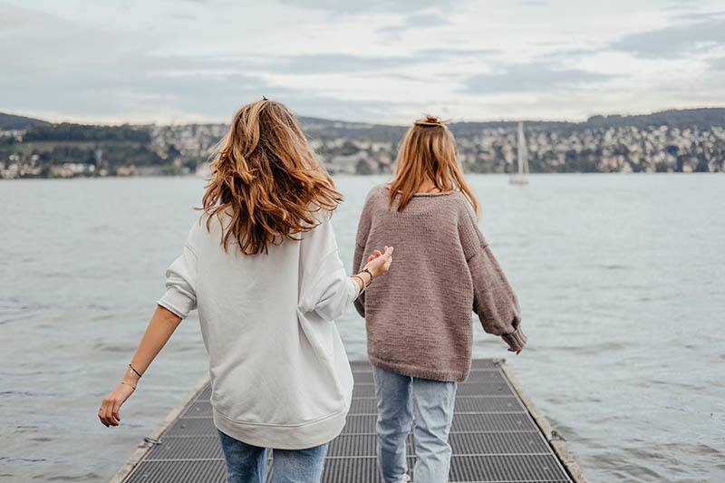 vista trasera de dos mujeres caminando en el muelle de un barco