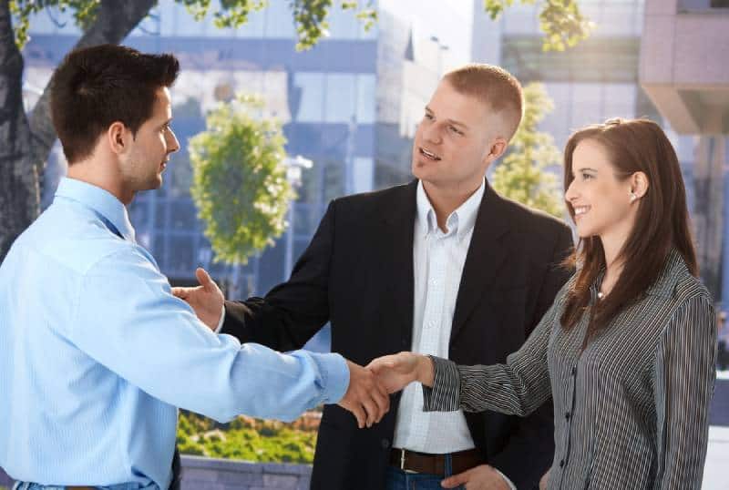 hombres de negocios reunidos en el exterior, un hombre presenta una mujer a su colega