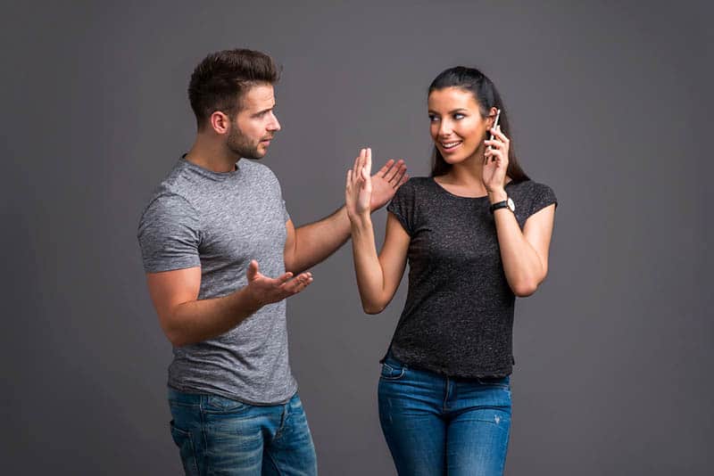 confused man looking at woman speaking on phone