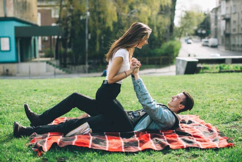 pareja pasandolo bien en el jardin sobre una manta