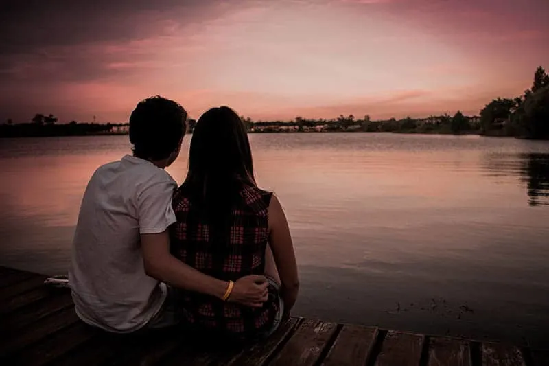 couple hugs on wooden dock in front of water