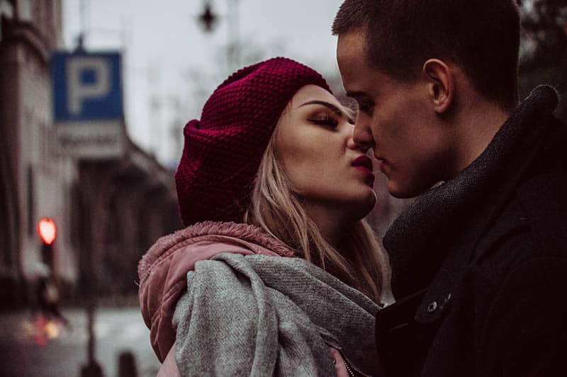 couple wearing jacket and kissing outside