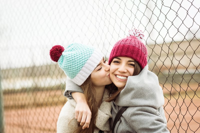 female friend kisses her best friend on cheek