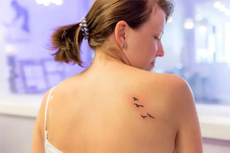 fresh tattoo of birds on womans shoulder