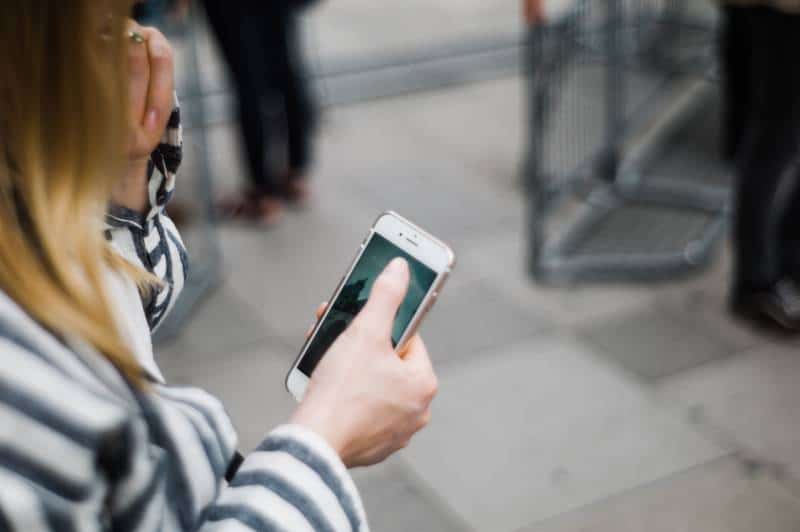 rapariga a escrever um telefone no exterior