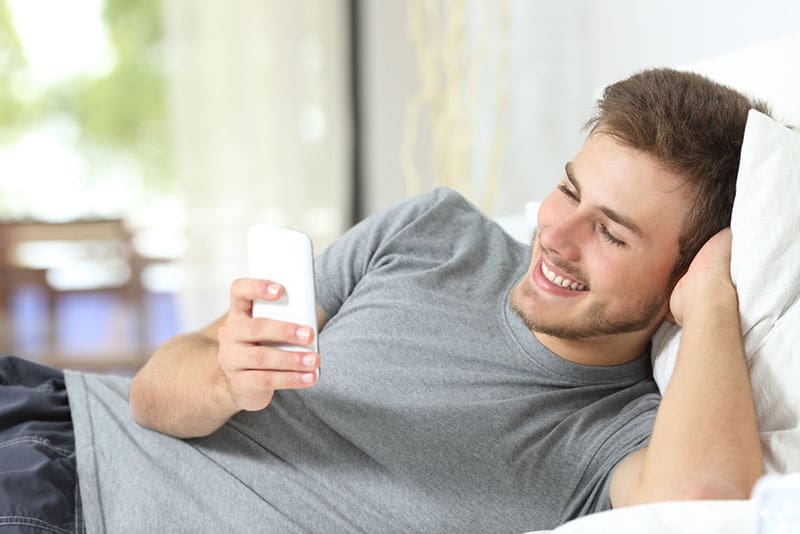 homem feliz a olhar para o telemóvel