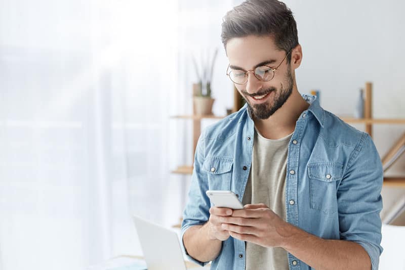 hombre feliz escribiendo en el teléfono