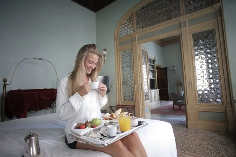 happy woman having breakfast on bed