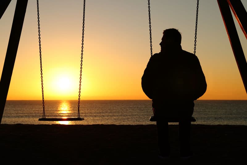 lonely man sitting on swingset