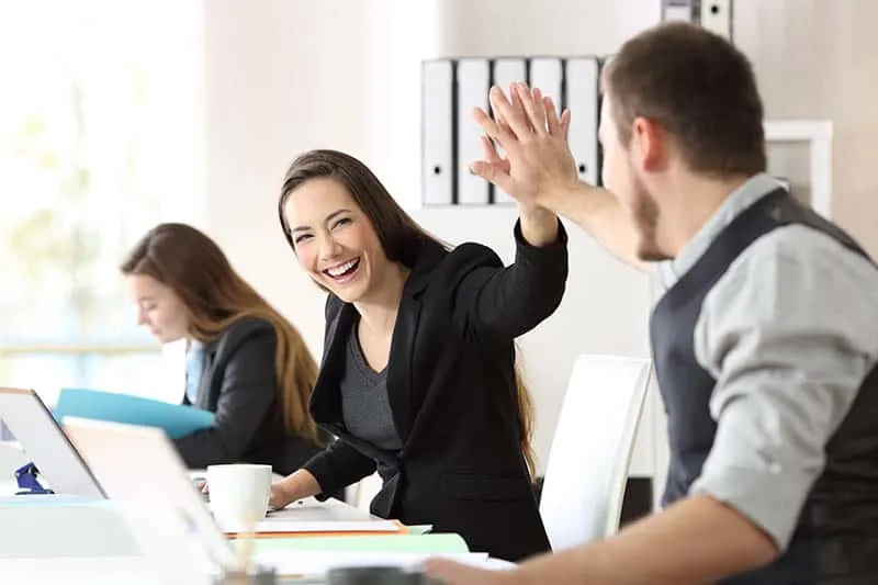 man and woman high five at office