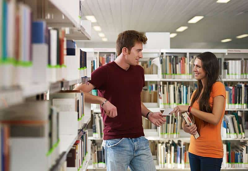 uomo e donna che parlano in biblioteca