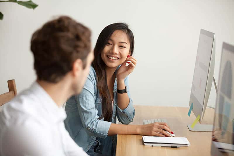 man and woman talking at office desk