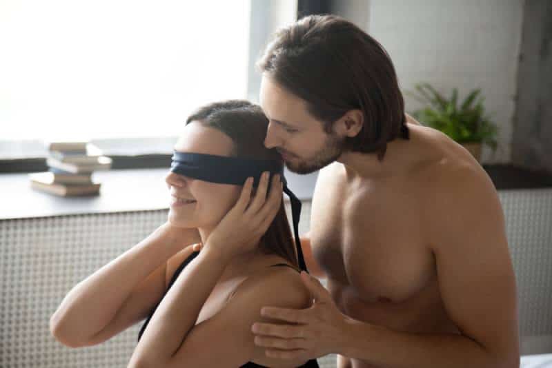 man gently touching blindfolded woman