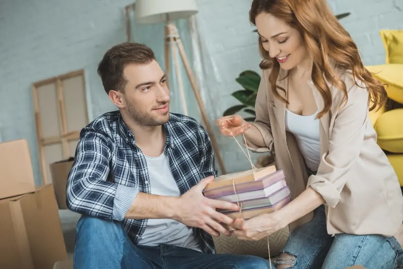 man helping to smiling woman with her books