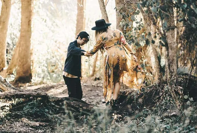 man helping woman to walk in nature