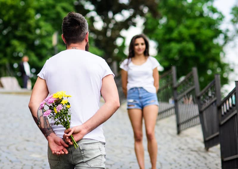 uomo con fiori in mano e in attesa della fidanzata