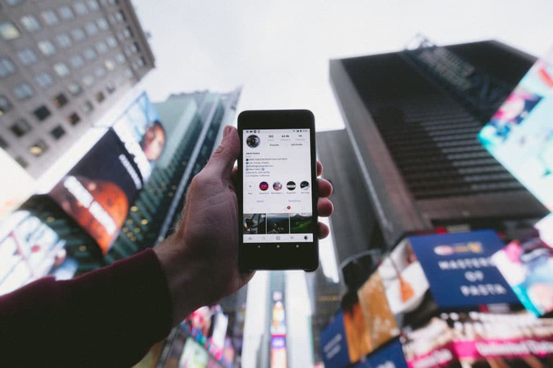 man holding phone and instagram account on