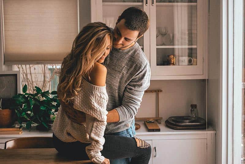 man hugs woman in the kitchen at home