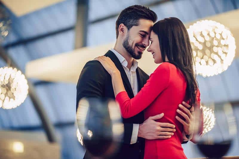 hombre con traje y mujer con vestido rojo abrazados