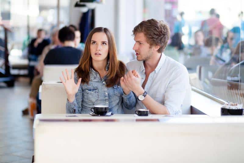 un hombre se disculpa con una mujer en un café