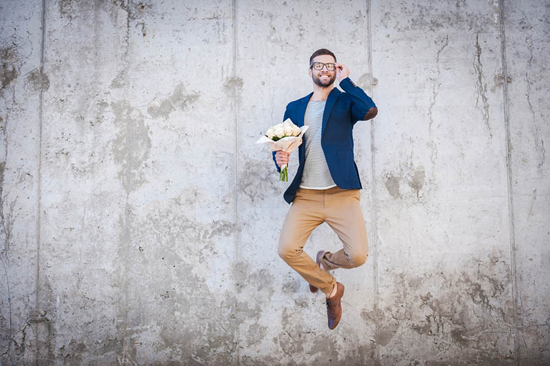 man jumps with flowers in hand