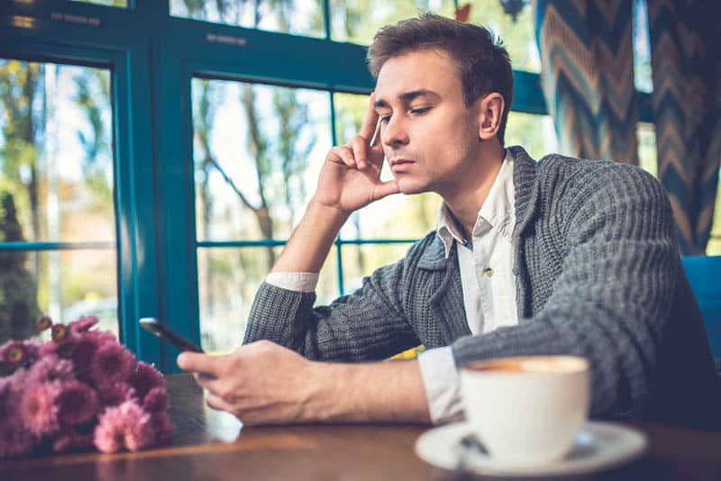 homem com ar sério enquanto olha para o seu telemóvel