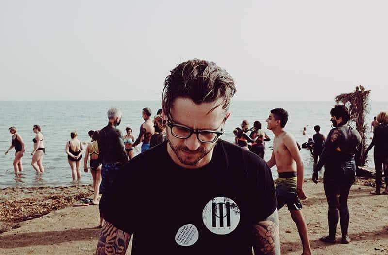 man wearing black shirt and eyeglasses walking on the beach