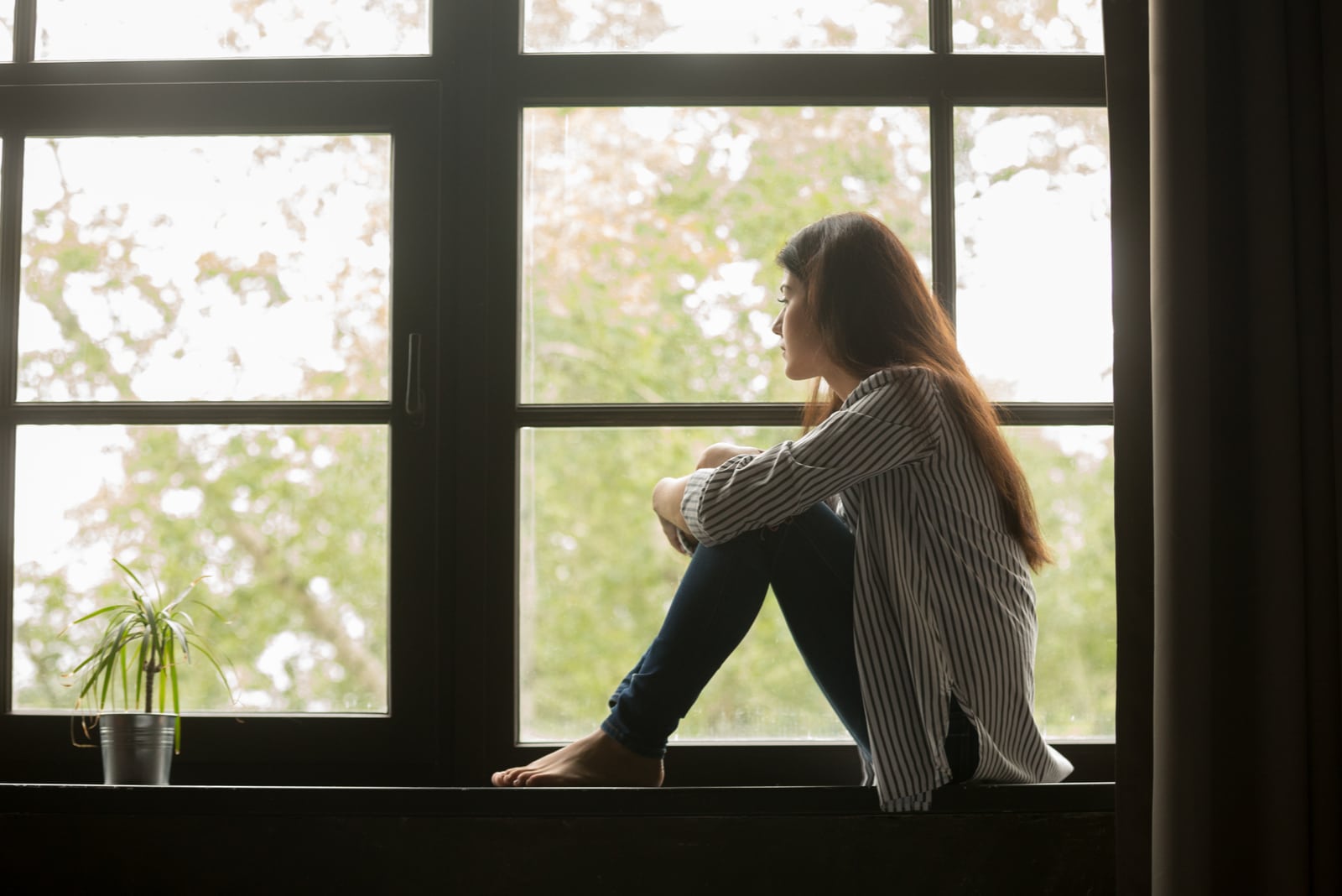 mindful woman sitting on big window